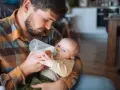 Padre con barba nutre il neonato con il biberon. Scopri trucchi per far prendere il biberon al tuo piccolo.