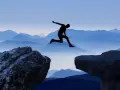 Silhouette di una persona che salta tra due rocce, con montagne blu sullo sfondo. Un viaggio per perdersi per ritrovarsi, un salto nel vuoto per una coppia.