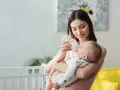Mamma sorridente nutre il neonato con latte artificiale. Il piccolo potrebbe avere cacca liquida, ma ora è felice.