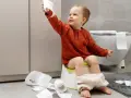 Bambino di 4 anni sul vasino, con rotoli di carta igienica sparsi. Un piccolo disastro, ma un grande passo verso l'indipendenza!