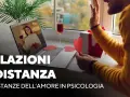 Coppia in videochiamata, lei con bicchiere di vino e regalo, lui saluta. Mi sento come se mio marito non mi desse attenzioni, ma la distanza è dura.