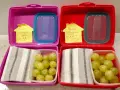 Due lunchbox rosa e rosse pronte per le merende per bambini, con uva e un bigliettino "Buona Merenda!".