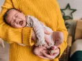 Neonato di 11 mesi con scatti nervosi, piange tra le braccia di chi lo tiene, avvolto in un maglione giallo.