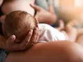Un neonato si nutre al seno, la sua testolina è tenuta da una mano. La montata lattea non arriva, ma l'amore è presente.