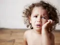 Bambino con riccioli castani piange, forse è un modo per comunicare il disagio, ecco perchè i bambini mordono.