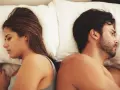 Coppia a letto, schiena contro schiena, con espressioni pensierose. Un'immagine che fa riflettere su come capire se una relazione è finita.