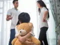 Bambina abbraccia orsacchiotto, mentre i genitori discutono. Avere coraggio di separarsi è difficile per tutti.