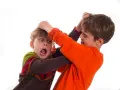 Due bambini che litigano, uno afferra i capelli dell'altro con espressione sorpresa e spaventata.