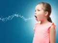Bambina con lettere che escono dalla bocca, simbolo dello sviluppo del linguaggio.