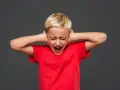 Bambino di 7 anni in crisi di rabbia, urla coprendosi le orecchie.