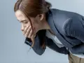 Donna con la mano sulla bocca, visibilmente sofferente, con la paura di vomitare.