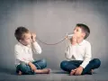 Due bambini comunicano con un telefono di latta. Come mio figlio ha iniziato a parlare a 4 anni, mi immagino che stiano condividendo segreti.