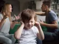 Bambino con le mani sulle orecchie, mentre i genitori litigano. Una scena che mostra una crisi di coppia con figli.