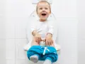 Bambino felice sul water, pantaloni abbassati, pronto per fare la cacca.