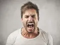 Uomo con espressione di forte rabbia, occhi chiusi e bocca spalancata. Potrebbe rappresentare le cause degli attacchi di rabbia.