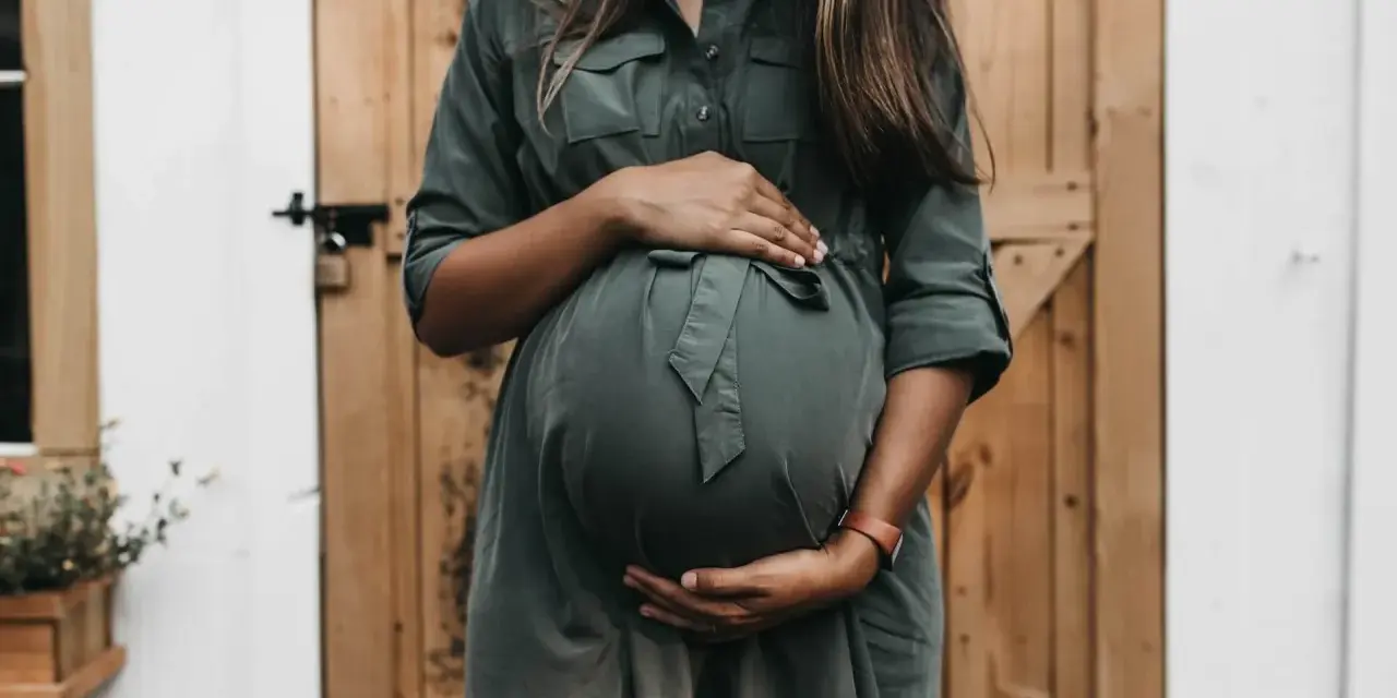 Donna incinta con mani sul pancione, in attesa di un bambino. Un momento di gioia che spesso include l'analisi sangue gravidanza.