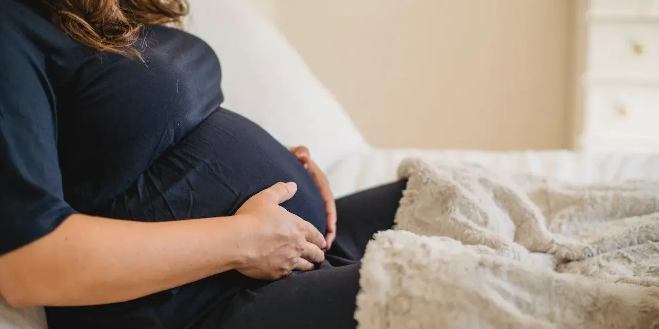 Donna incinta accarezza il pancione, preoccupata per la possibile escherichia coli in gravidanza.