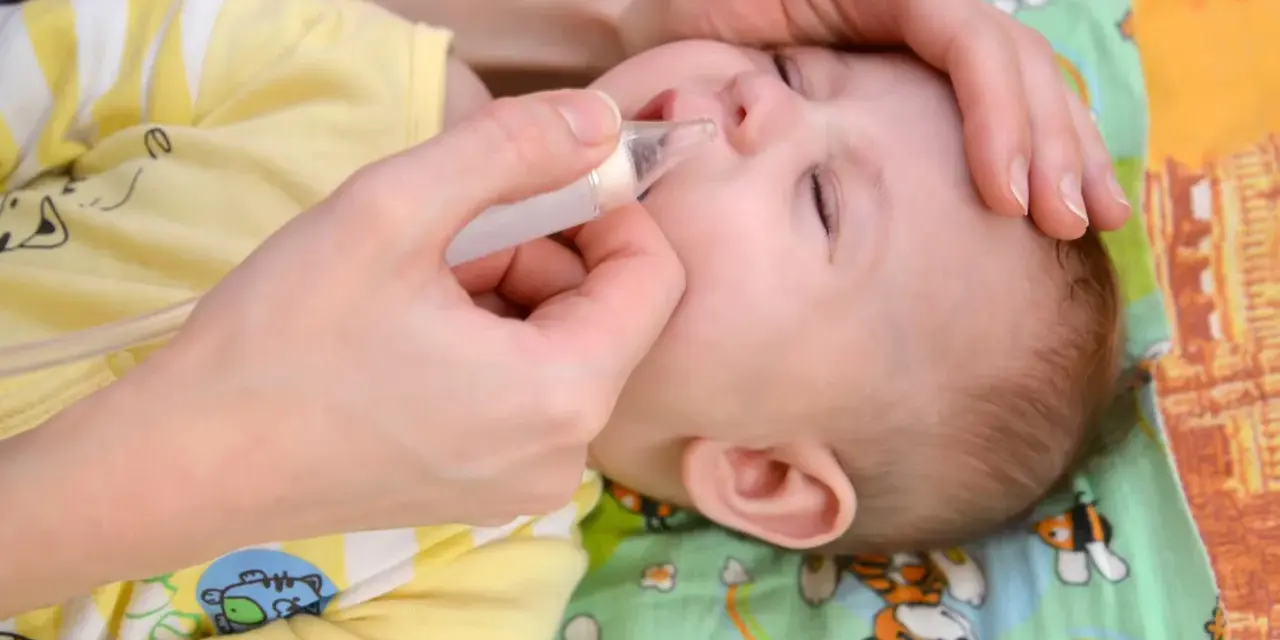 Mani che aiutano un neonato a liberare il naso dal muco, evitando il soffocamento.