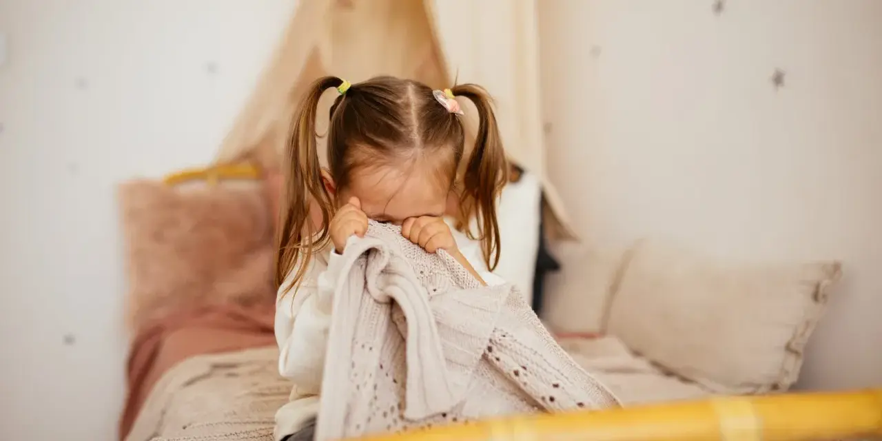 Bambina di 5 anni si nasconde nel plaid, forse per le paure notturne.