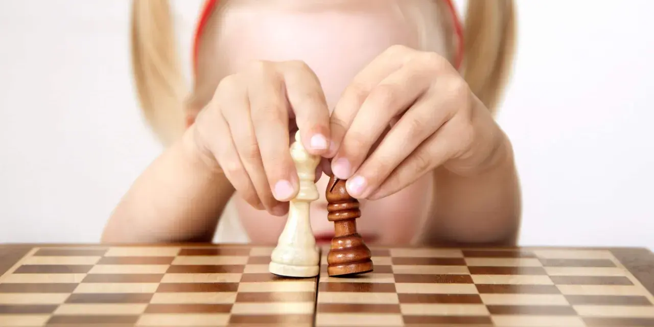 Bambino 3 anni non accetta regole: le sue mani manipolano i pezzi degli scacchi, creando una sua personale partita.