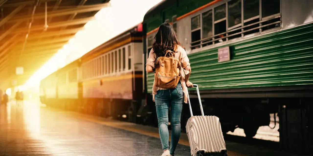 Donna con zaino e trolley in stazione, pronta a cambiare vita a 30 anni.