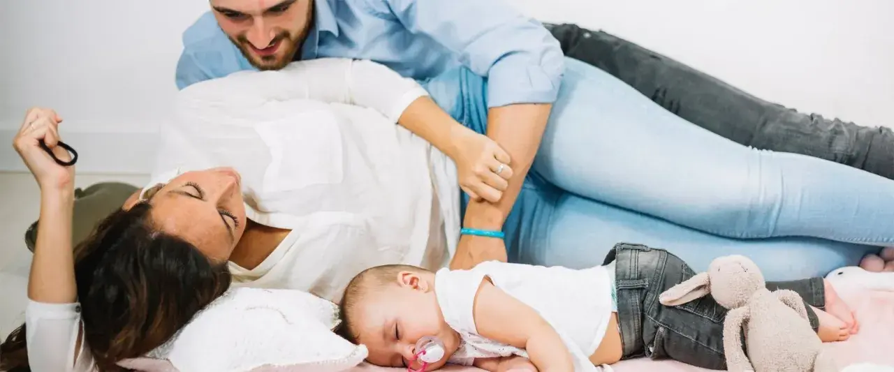 Un neonato dorme sereno tra i genitori. Un momento di pace, un nuovo inizio, quando si ricomincia a vivere dopo un figlio.