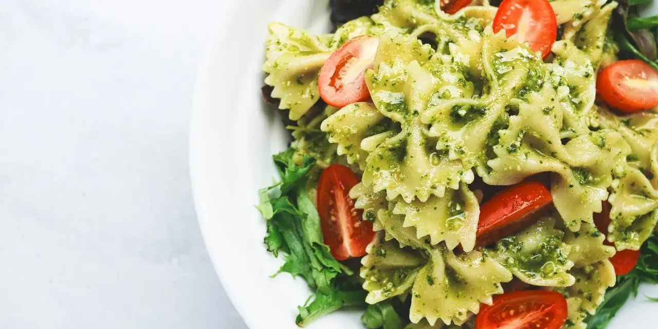 Deliziosa pasta fredda per bambini, con farfalle al pesto e pomodorini freschi, un piatto colorato e gustoso.