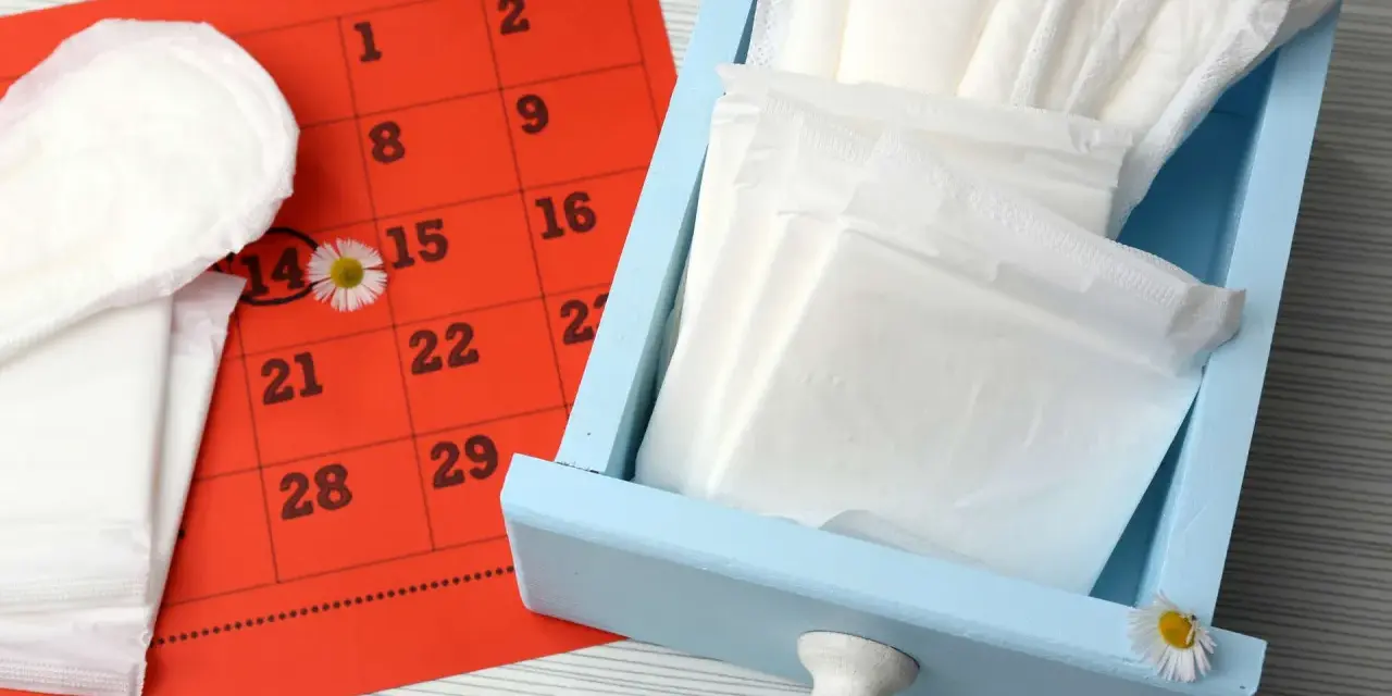 Calendario rosso con cerchiato il 14, assorbenti e fiori di campo. Nessun segno di sangue durante ovulazione incinta.
