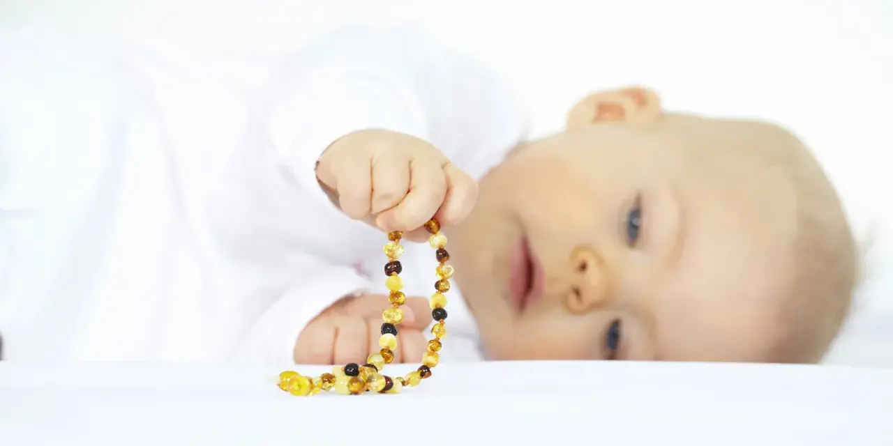 Bambino con collana ambra neonati pericolosa. Attenzione ai rischi di soffocamento e strangolamento.