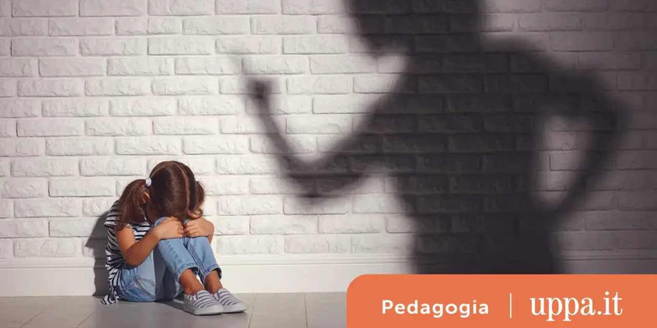 Bambina spaventata seduta a terra, ombra minacciosa di un adulto. Un'immagine che evoca le conseguenze delle punizioni corporali sui bambini.
