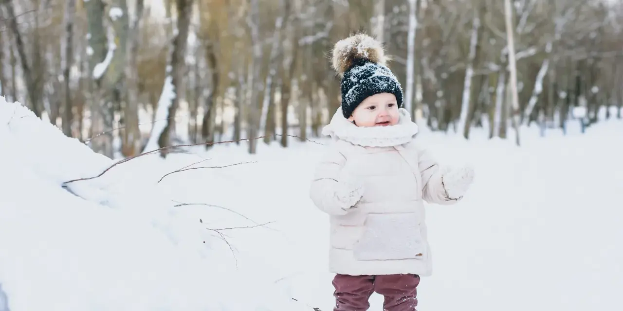 Bambino in montagna, con cappello di lana e guanti, immerso nella neve. Un'avventura invernale per i più piccoli.