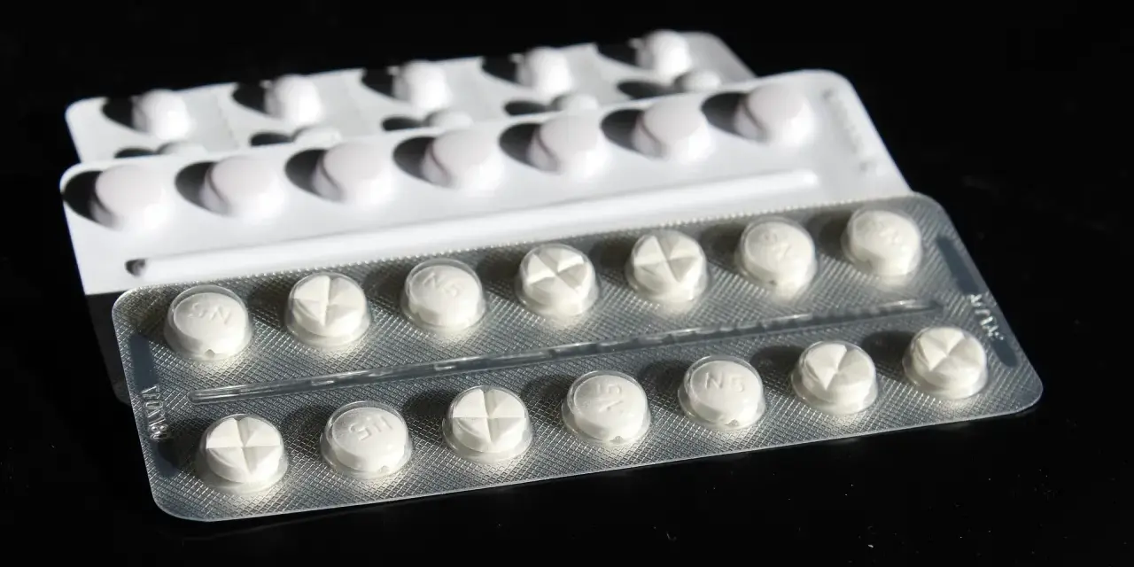 Blister di pillole bianche, alcune con incisione a croce. Potrebbe trattarsi di cardioaspirina in gravidanza, un farmaco da usare con cautela.