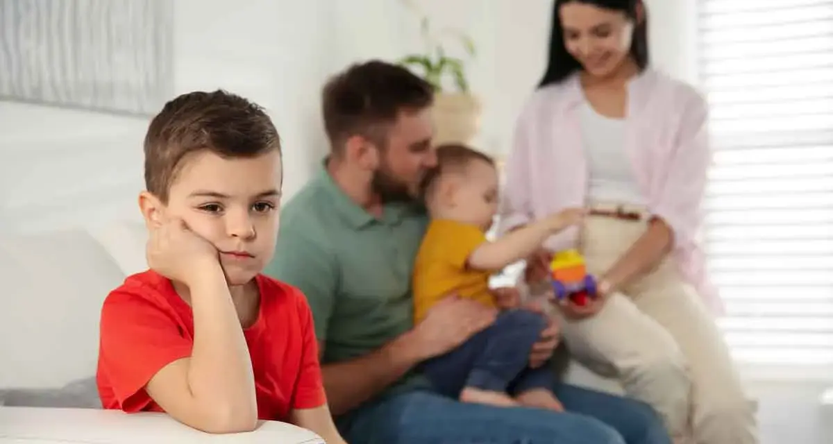 Bambino annoiato, forse per la nascita del fratellino e le conseguenti crisi isteriche. La famiglia è sullo sfondo.
