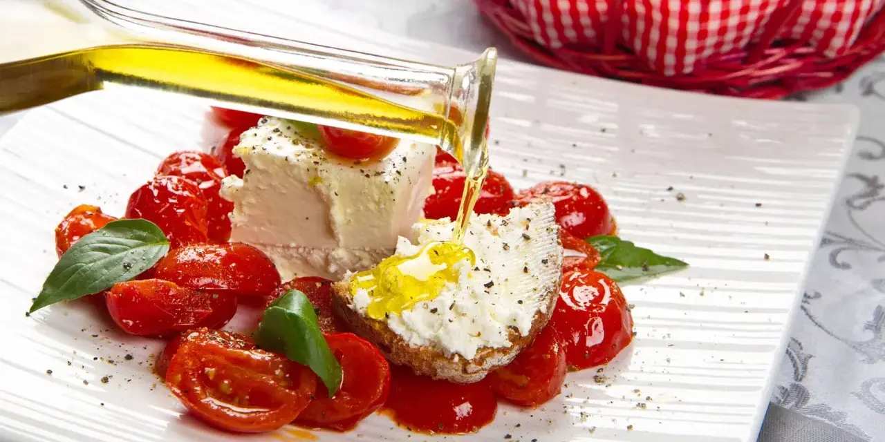 Un piatto di pomodorini confit con robiola, perfetto per una gravidanza sana e gustosa. Olio d'oliva versato su una fetta di pane con formaggio.