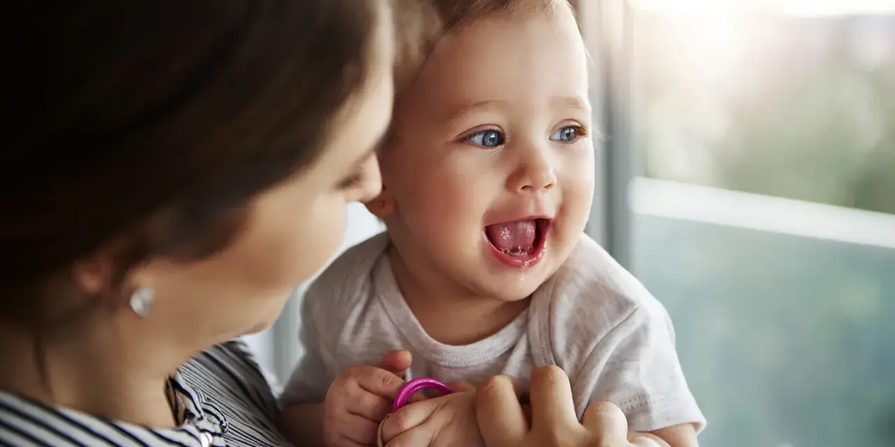 Bambino sorridente con mamma, forse è l'inizio della lallazione.