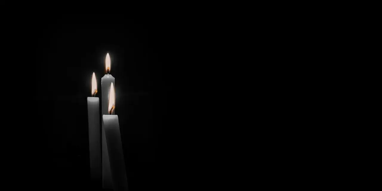 Tre candele accese nel buio, un'immagine che evoca il **stress da lutto sintomi fisici**, come il senso di vuoto e la fragilità.