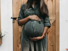 Donna incinta con mani sul pancione, in attesa di un bambino. Un momento di gioia che spesso include l'analisi sangue gravidanza.