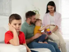 Bambino annoiato, forse per la nascita del fratellino e le conseguenti crisi isteriche. La famiglia è sullo sfondo.