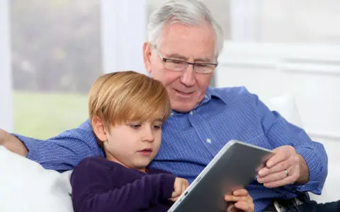 Nonni che non aiutano, ma osservano il nipote giocare sul tablet.