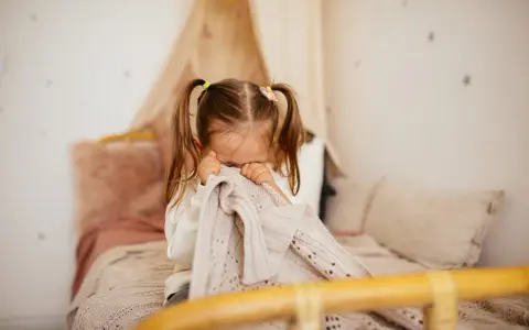 Bambina di 5 anni si nasconde nel plaid, forse per le paure notturne.
