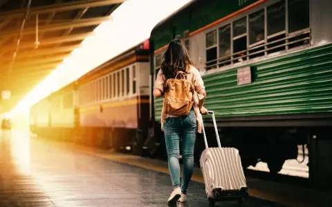 Donna con zaino e trolley in stazione, pronta a cambiare vita a 30 anni.