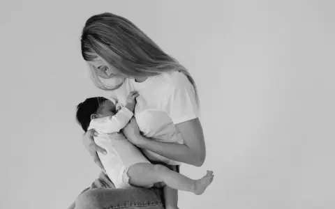 Madre con neonato in braccio, un momento intimo di allattamento. Non c'è traccia di fumare in allattamento, solo amore e cura.