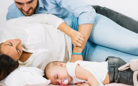 Un neonato dorme sereno tra i genitori. Un momento di pace, un nuovo inizio, quando si ricomincia a vivere dopo un figlio.
