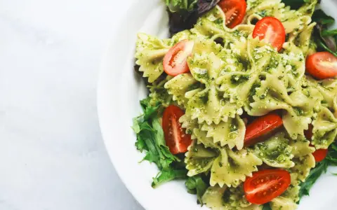 Deliziosa pasta fredda per bambini, con farfalle al pesto e pomodorini freschi, un piatto colorato e gustoso.