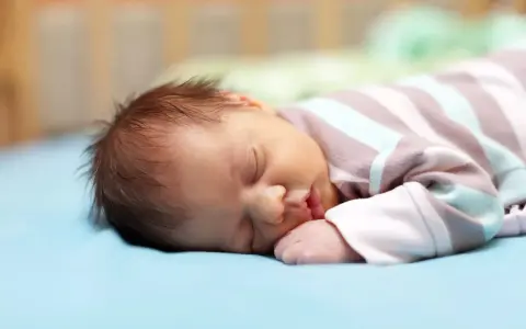 Un neonato dorme sereno, ma chissà se i neonati sognano incubi. La sua manina è vicino alla bocca, il pigiamino a righe lo avvolge.