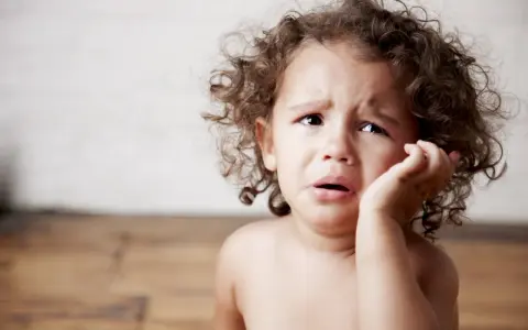 Bambino con riccioli castani piange, forse è un modo per comunicare il disagio, ecco perchè i bambini mordono.