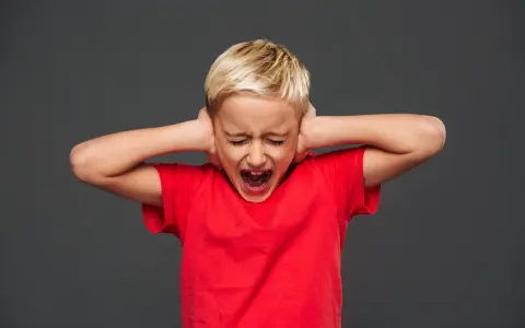 Bambino di 7 anni in crisi di rabbia, urla coprendosi le orecchie.