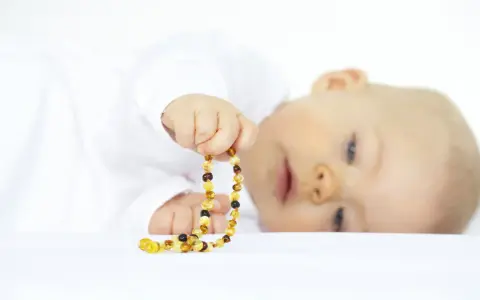 Bambino con collana ambra neonati pericolosa. Attenzione ai rischi di soffocamento e strangolamento.