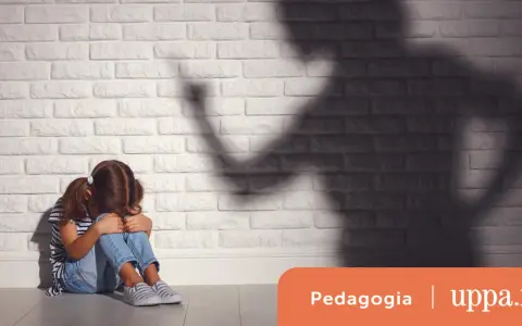 Bambina spaventata seduta a terra, ombra minacciosa di un adulto. Un'immagine che evoca le conseguenze delle punizioni corporali sui bambini.