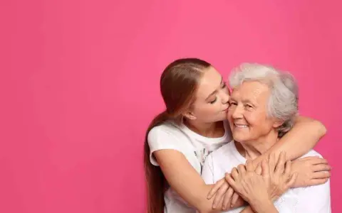 Una ragazza bacia la guancia della nonna, abbracciandola. Si vede che i figli assomigliano ai nonni, un legame d'amore.